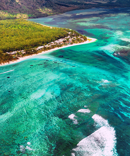 Turquoise water beside a forested tropical coastline